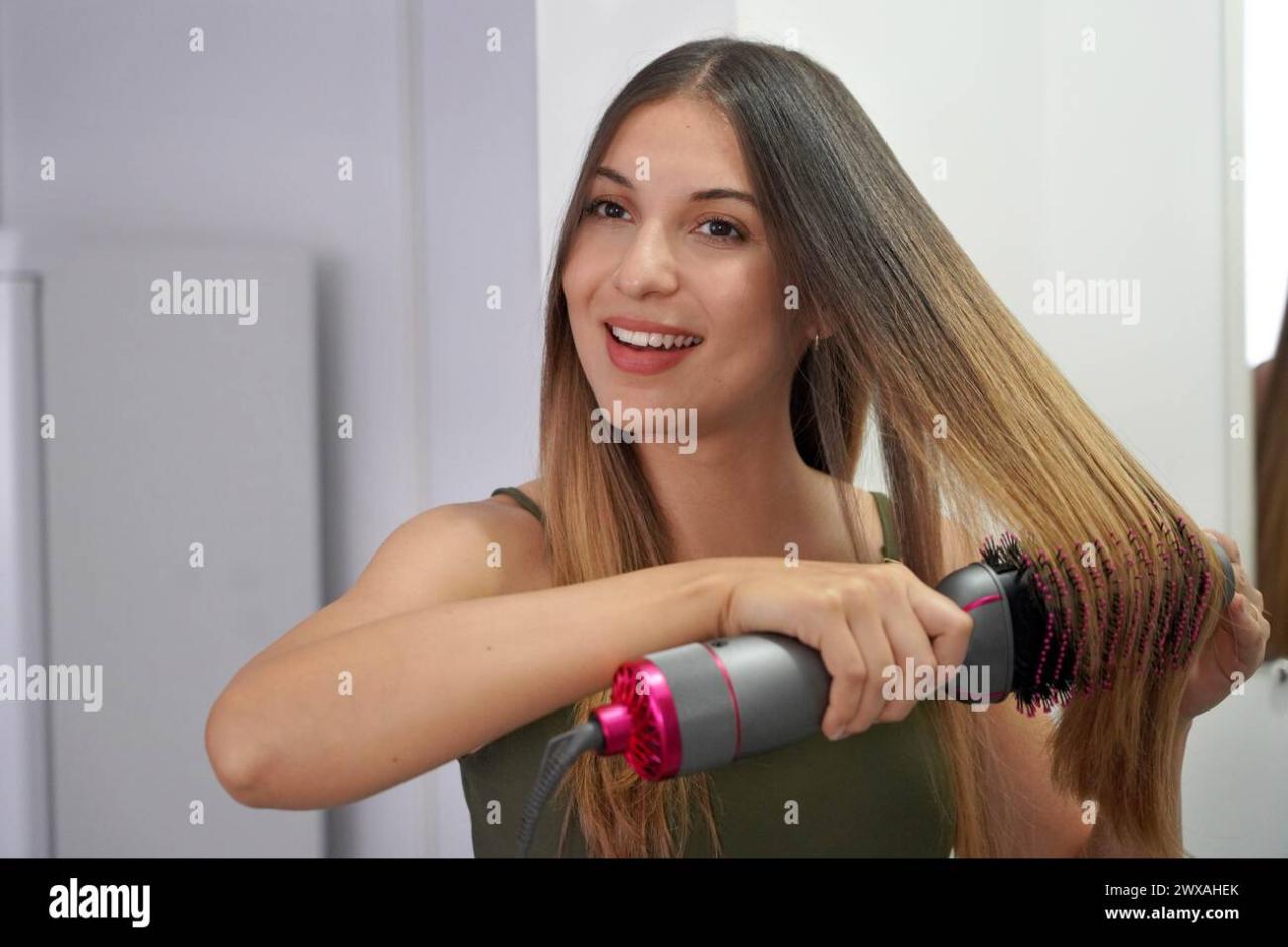 Hot air hair brush. Young woman using round brush hair dryer to style ... Hot air hair brush. Young woman using round brush hair dryer to style ...
